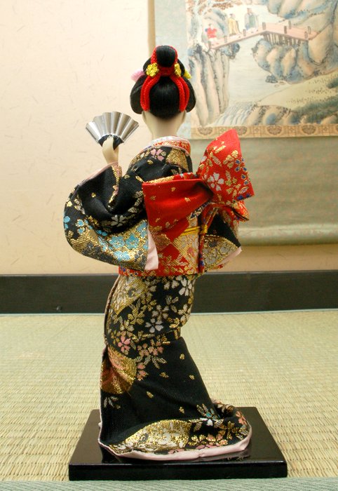 Cette poupée antique japonaise habillée en kimono multicolore avec